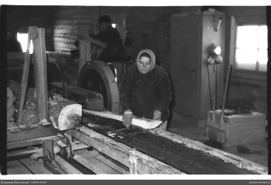 Frau mit Holzklotz an Bandsäge