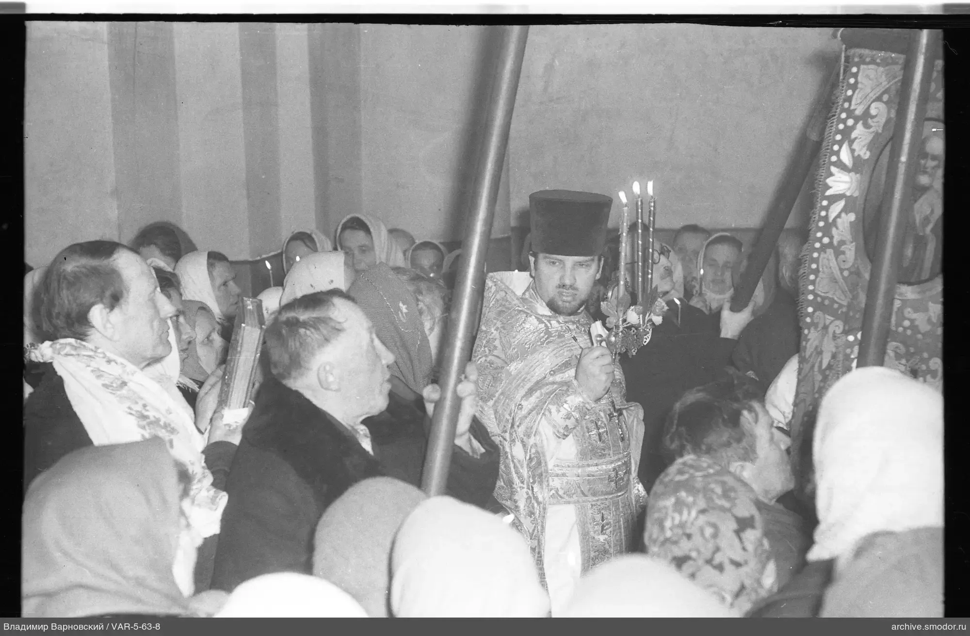 Священник с горящей свечой и группа людей