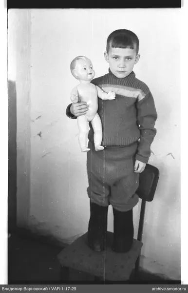 Junge mit Puppe auf einem Stuhl