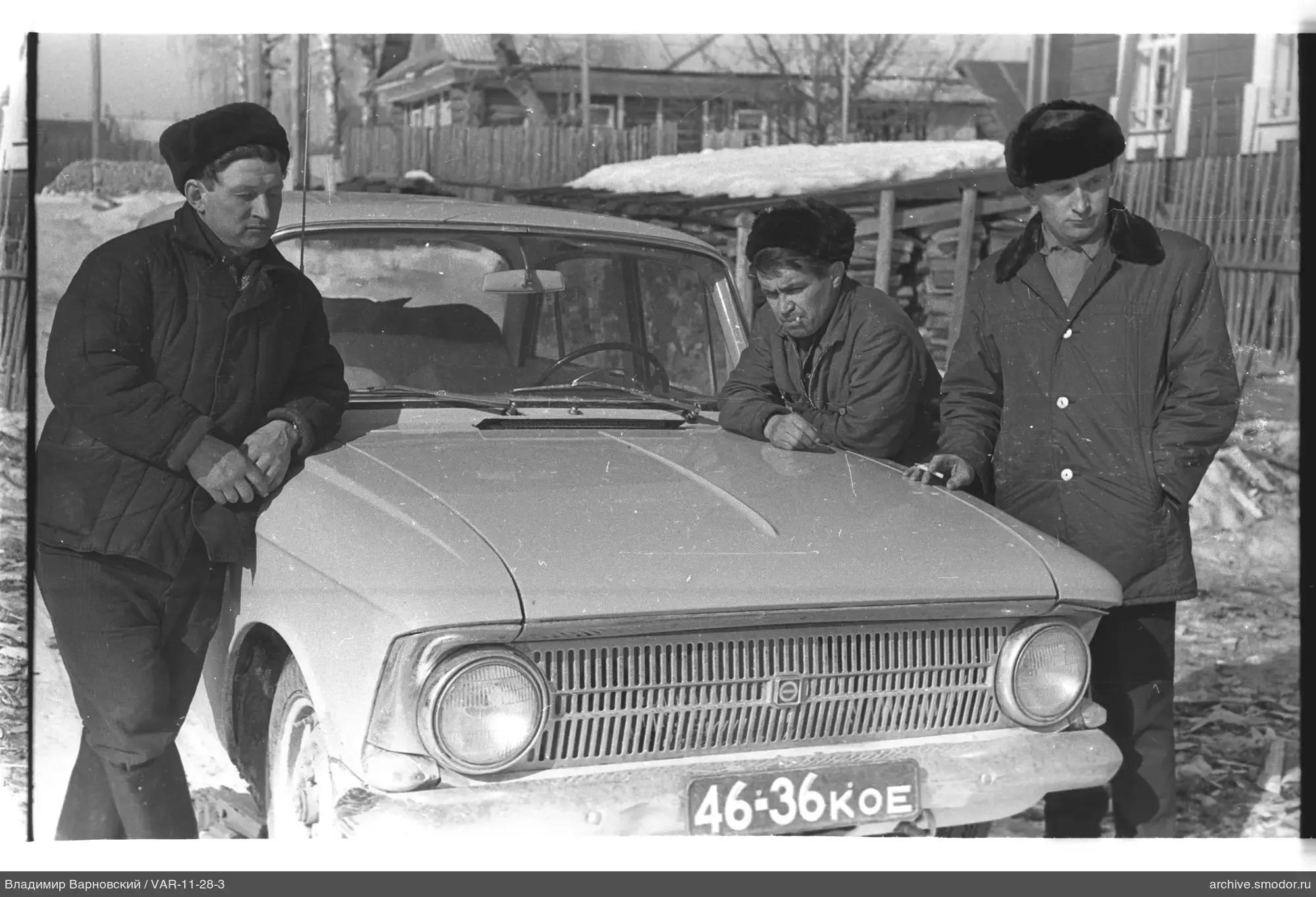 Drei Männer in Winterkleidung bei einem Auto