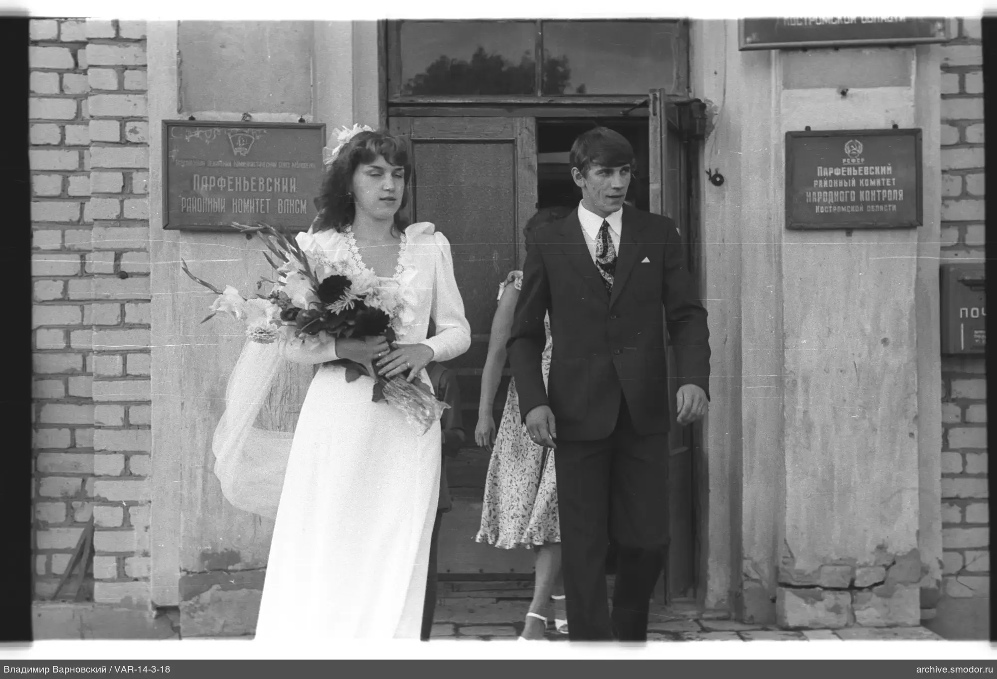 Young woman with bouquet and man exiting building