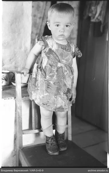 Child standing on a chair in a dress
