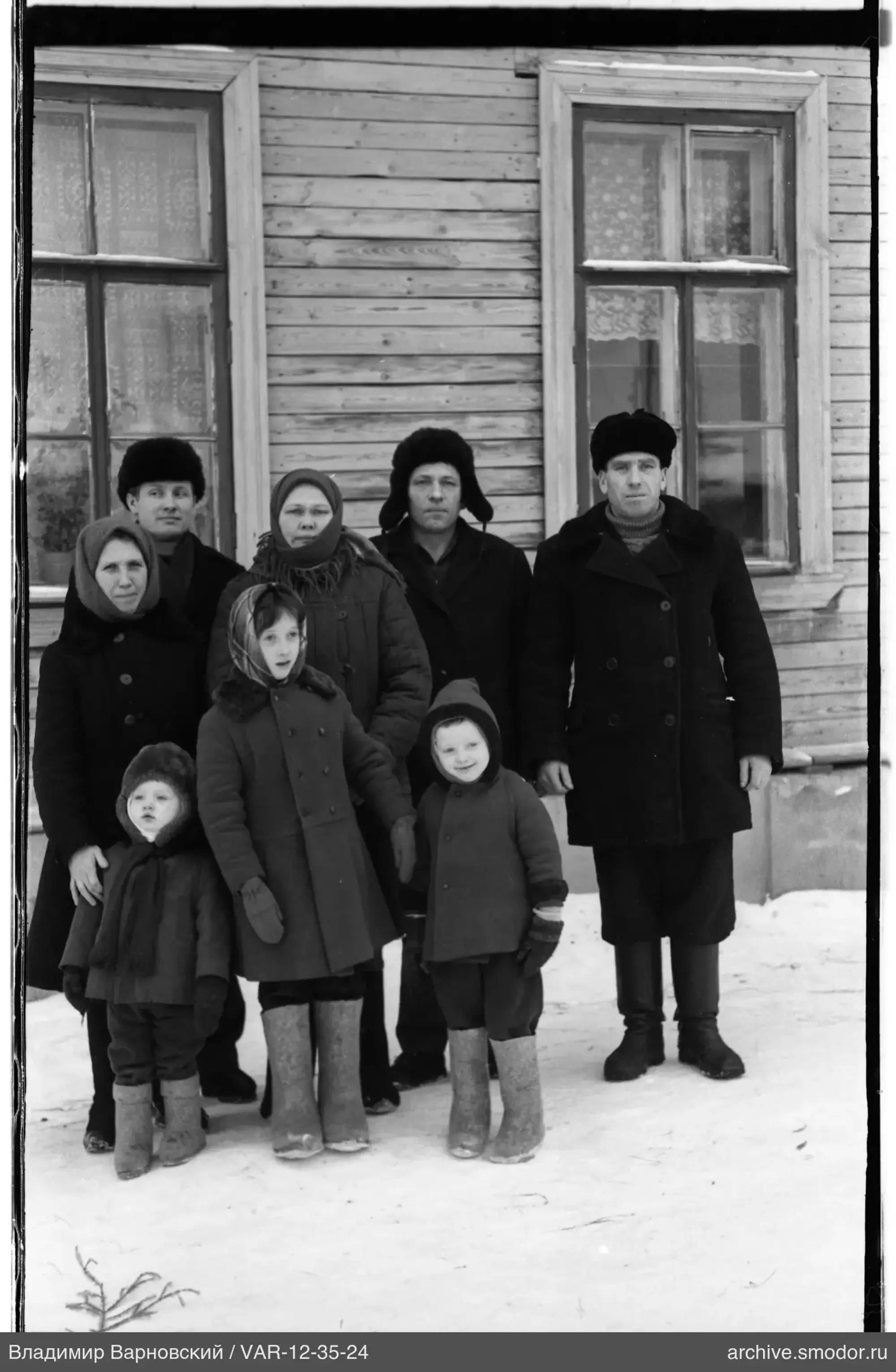Группа людей перед деревянным домом на снегу