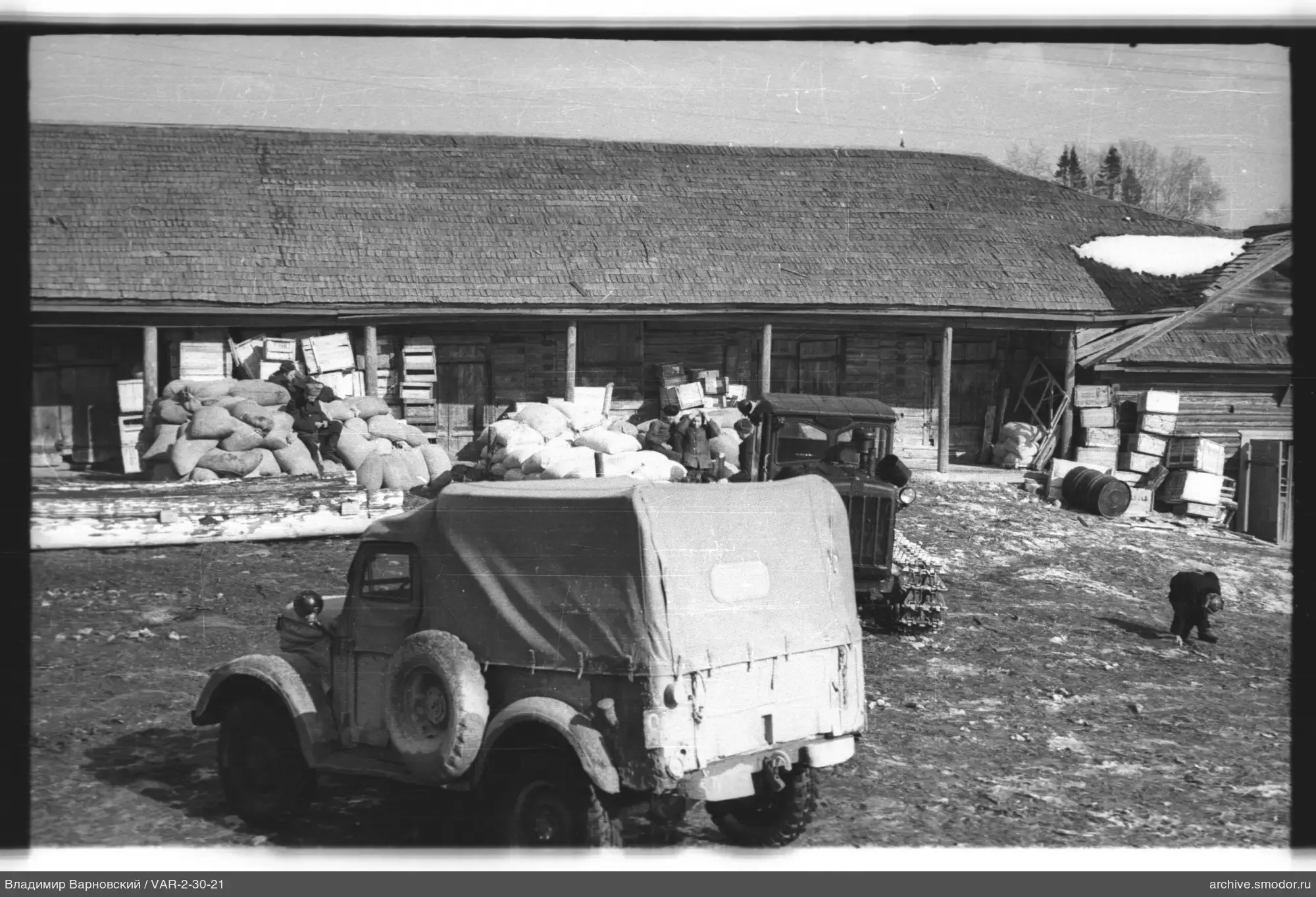 Fahrzeuge und Personen vor Holzgebäude