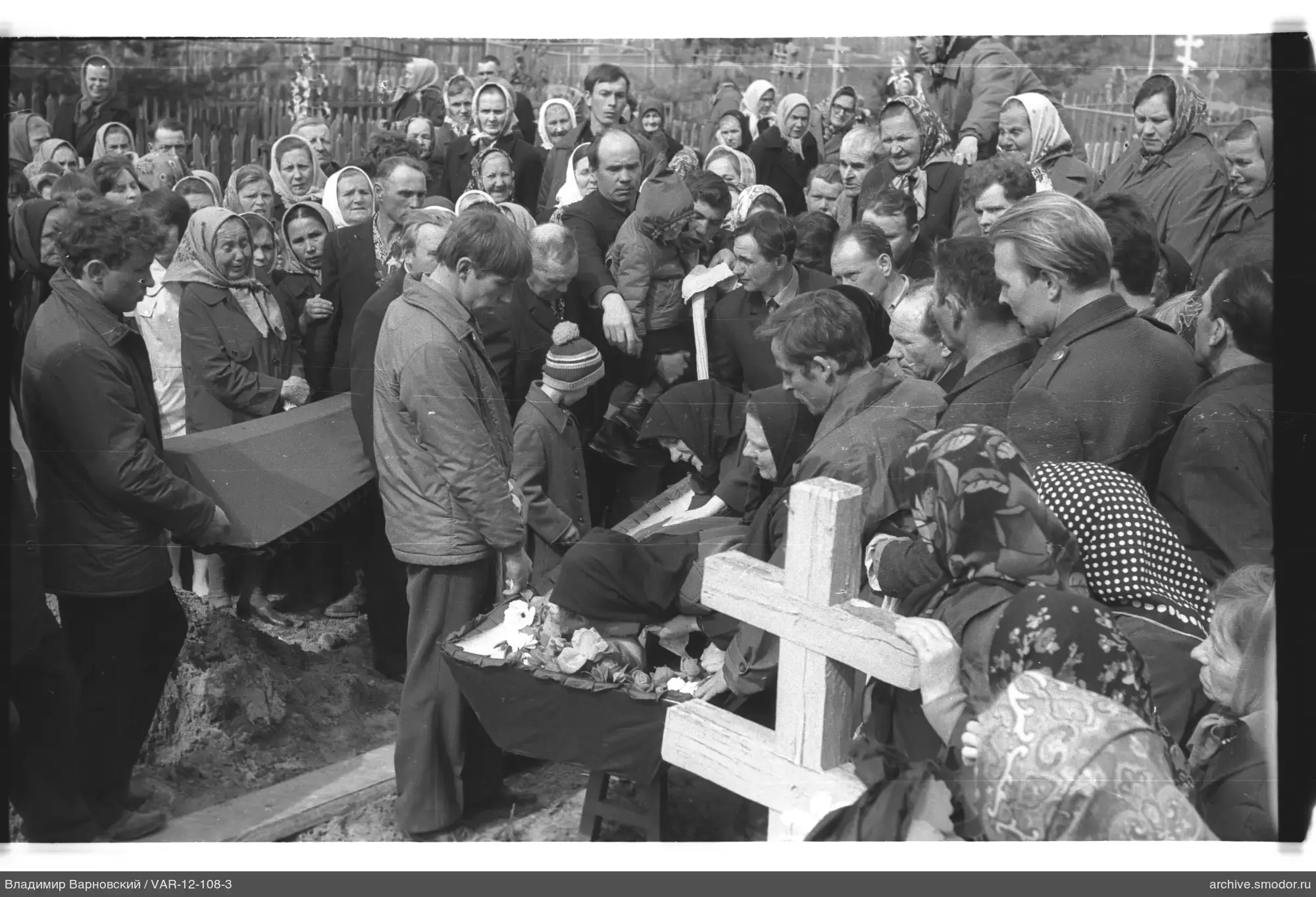Group of people around a coffin at a funeral