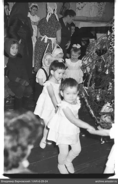 Kinder und Frauen bei geschmücktem Weihnachtsbaum