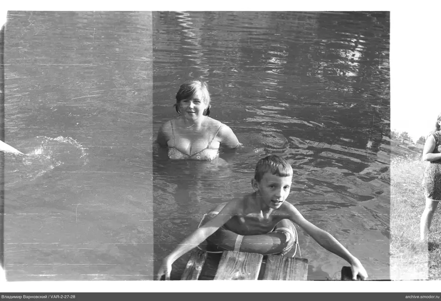 Kinder im Wasser und Frau am Ufer