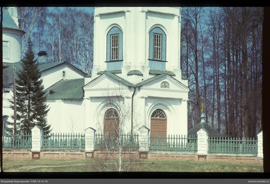 White building with arched windows and green fence