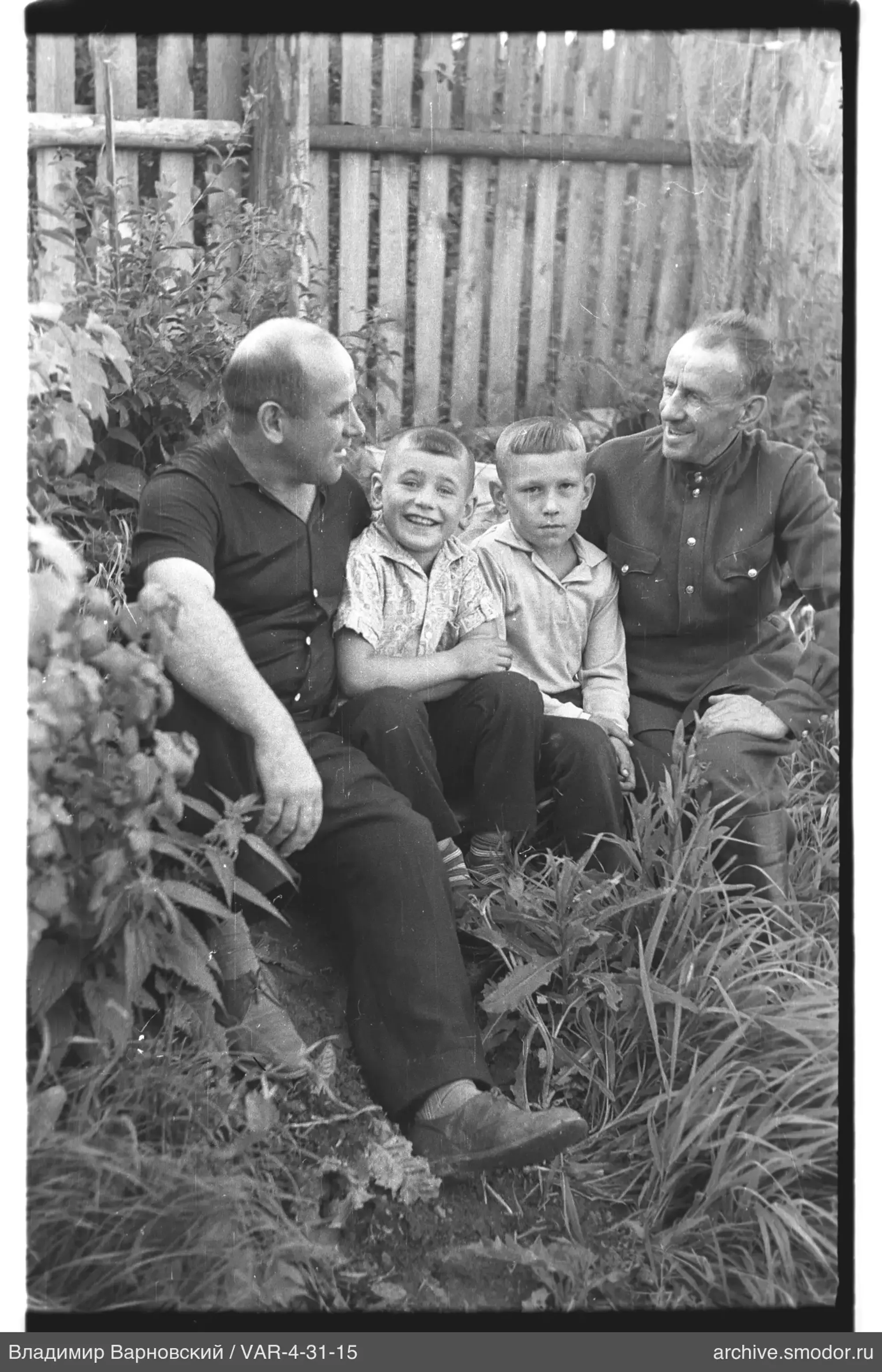 Group of people sitting by a wooden fence