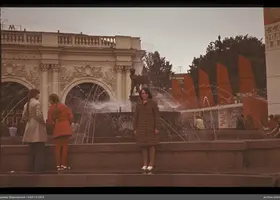 Frau am Brunnen und Mädchen vor Gebäude