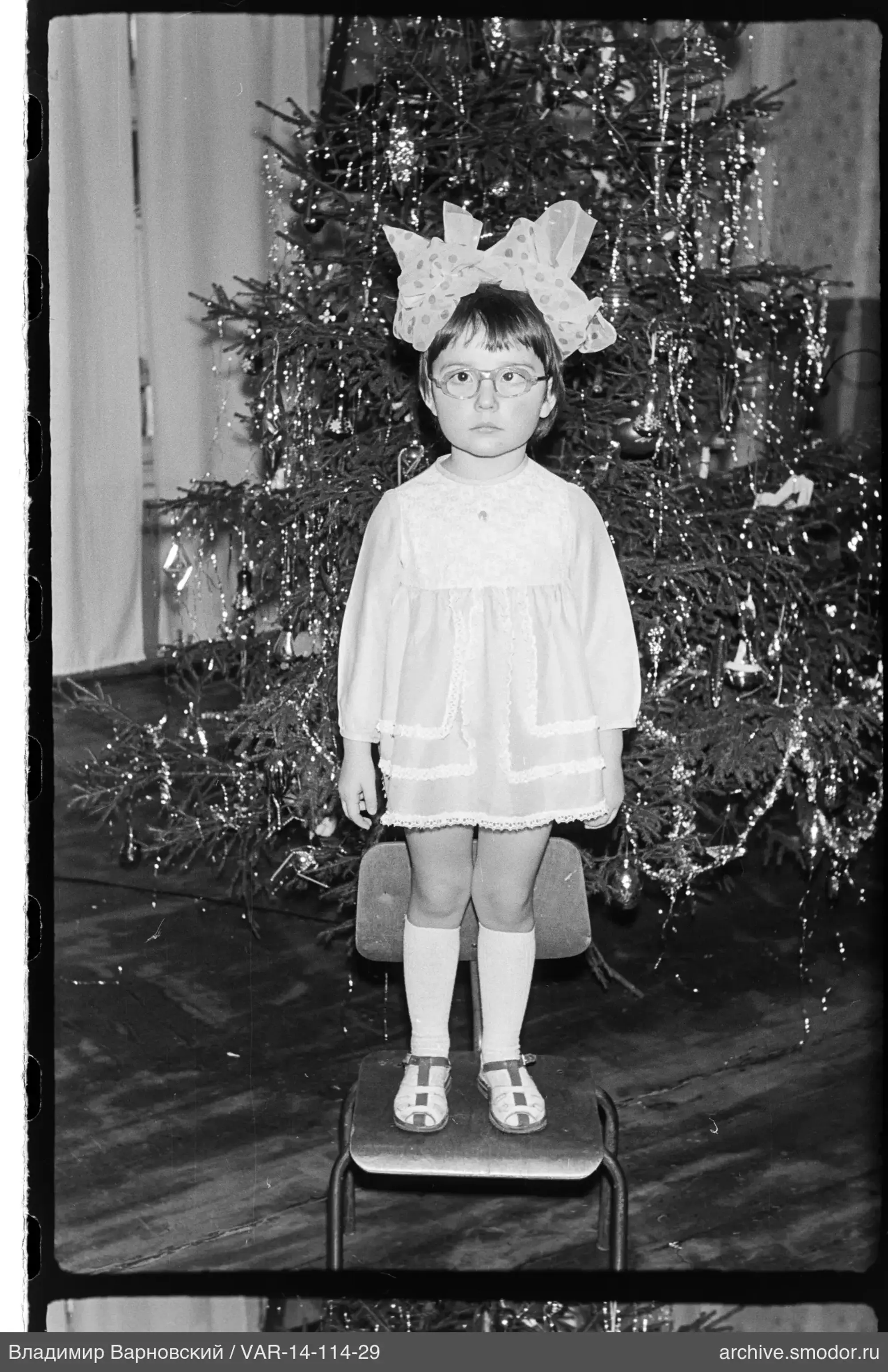 Mädchen mit Schleife vor Weihnachtsbaum