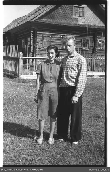 Mann und Frau vor einem Holzhaus
