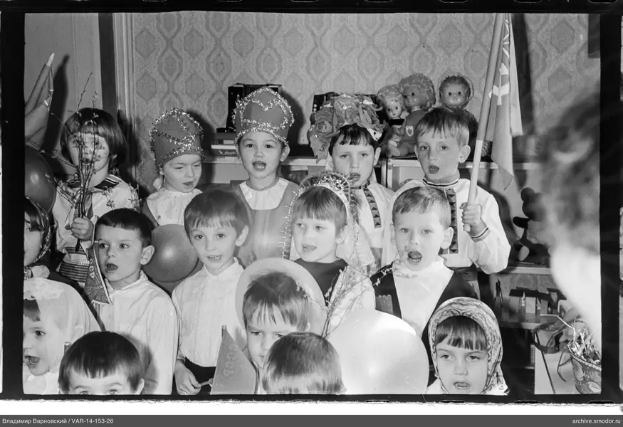 Kinder in festlichen Kostümen mit Fahnen und Ballons