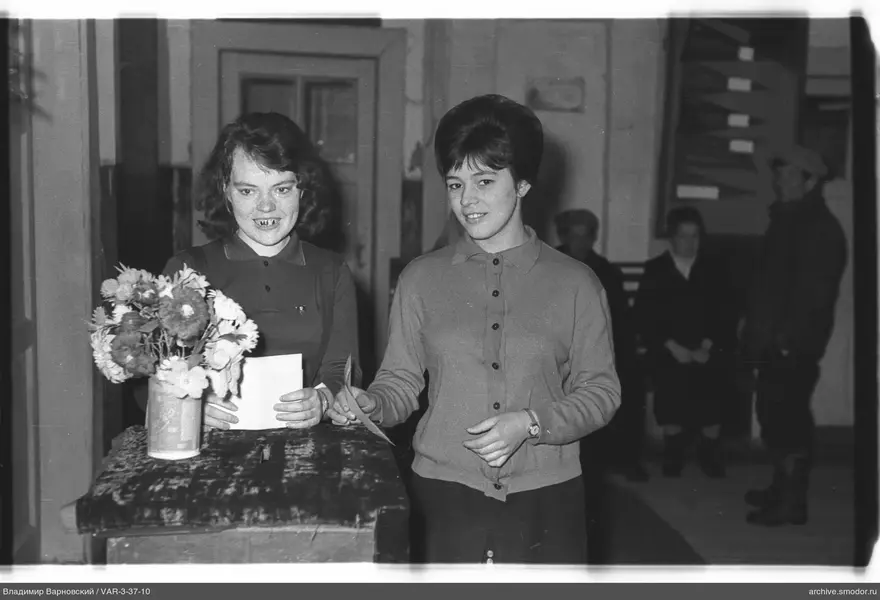 Two women with papers at a floral table