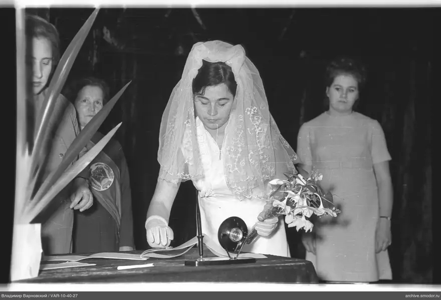 Woman in white dress and lace veil signing document