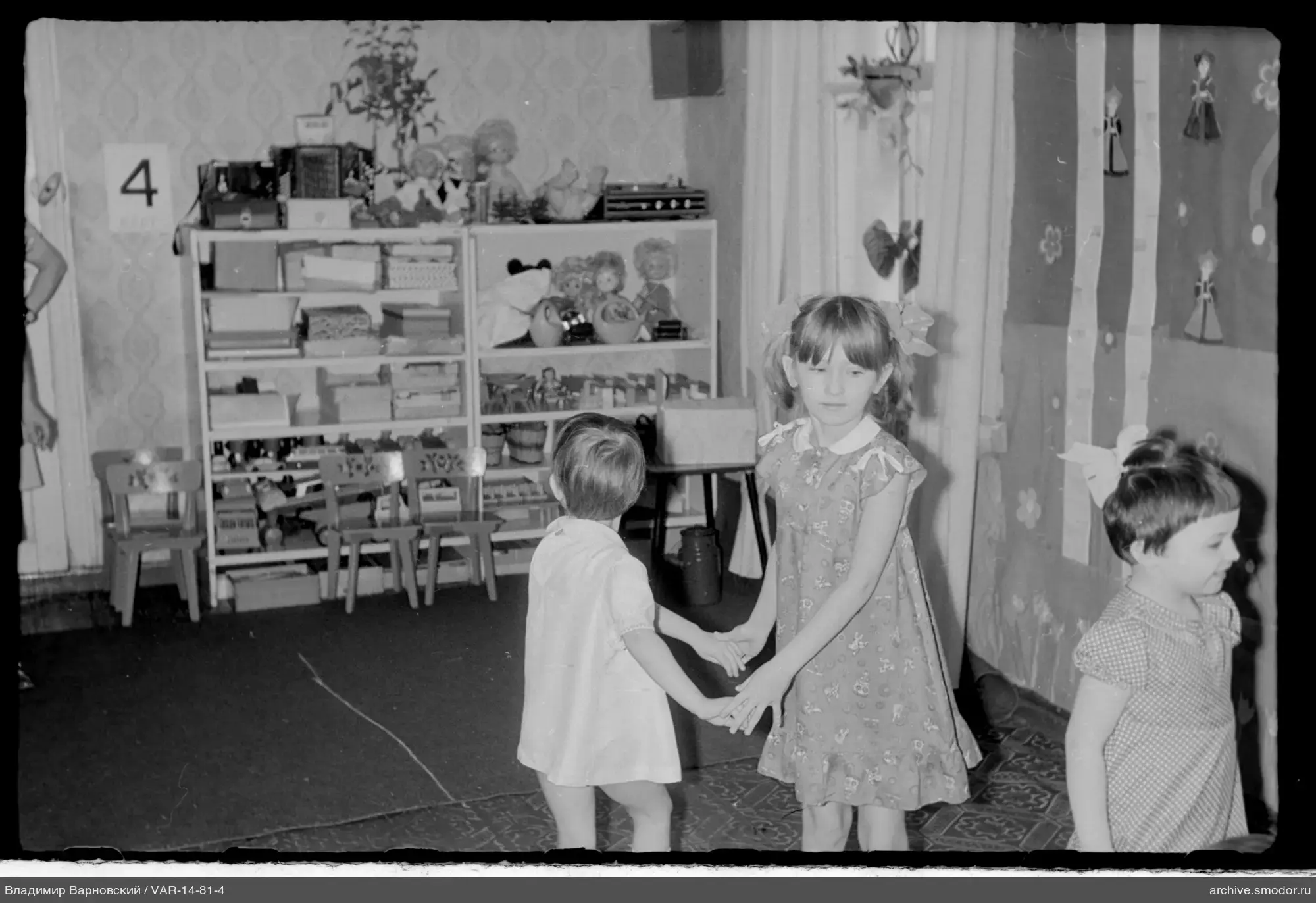 Kinder in einem Raum mit Spielzeug und gemusterter Tapete