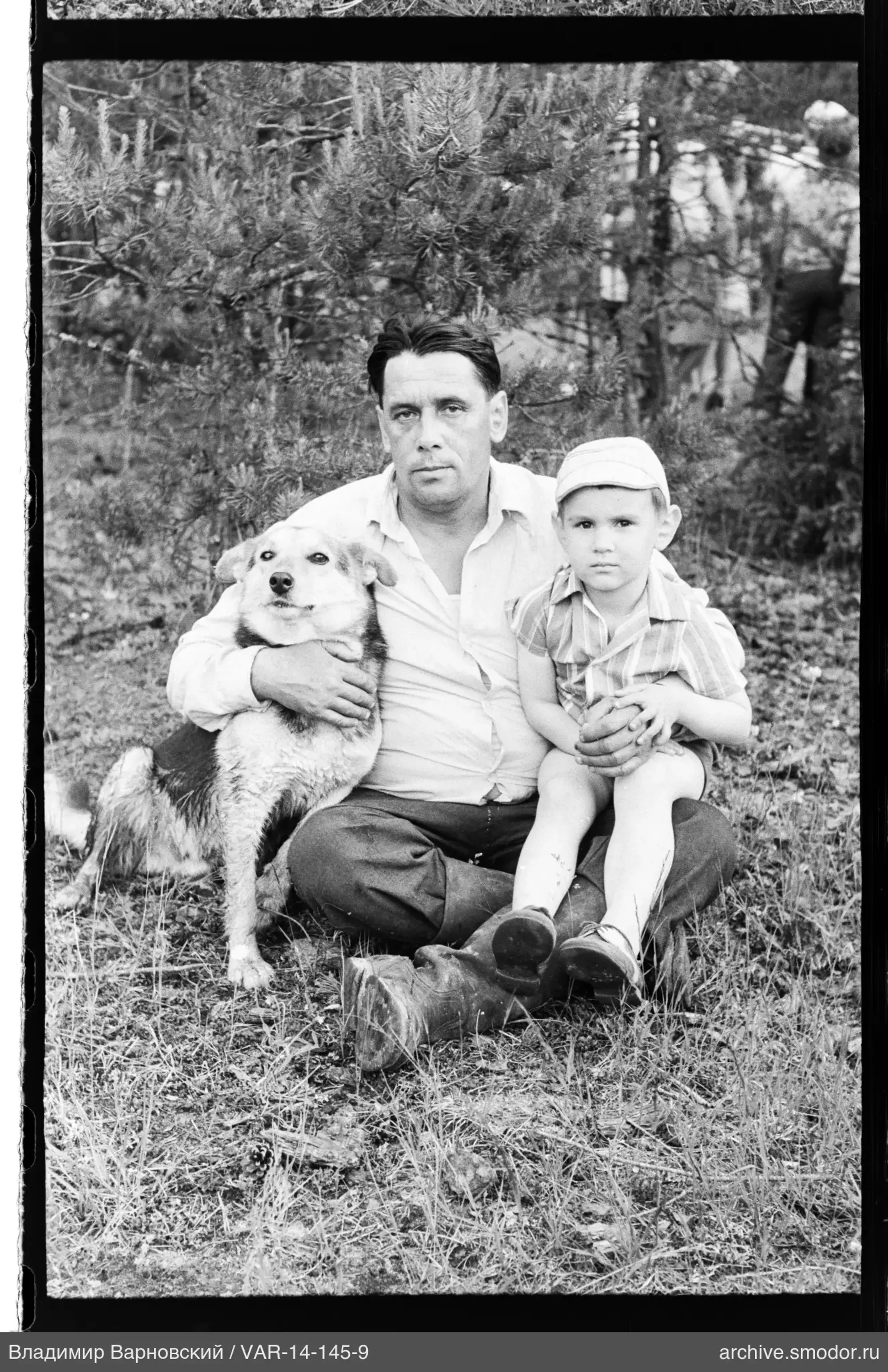 Mann mit Hund und Kind auf dem Gras