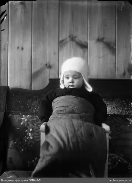 Ребёнок в шапке на деревянном стуле