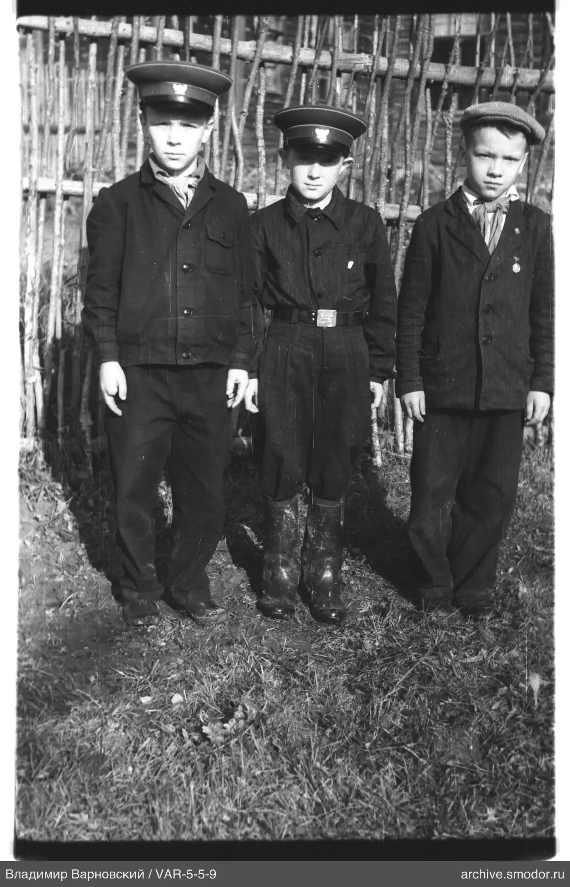 Three boys in front of a fence
