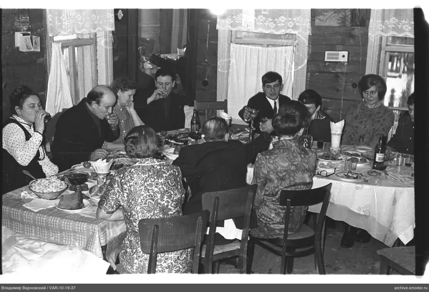 Мужчины и женщины за столами с едой и напитками