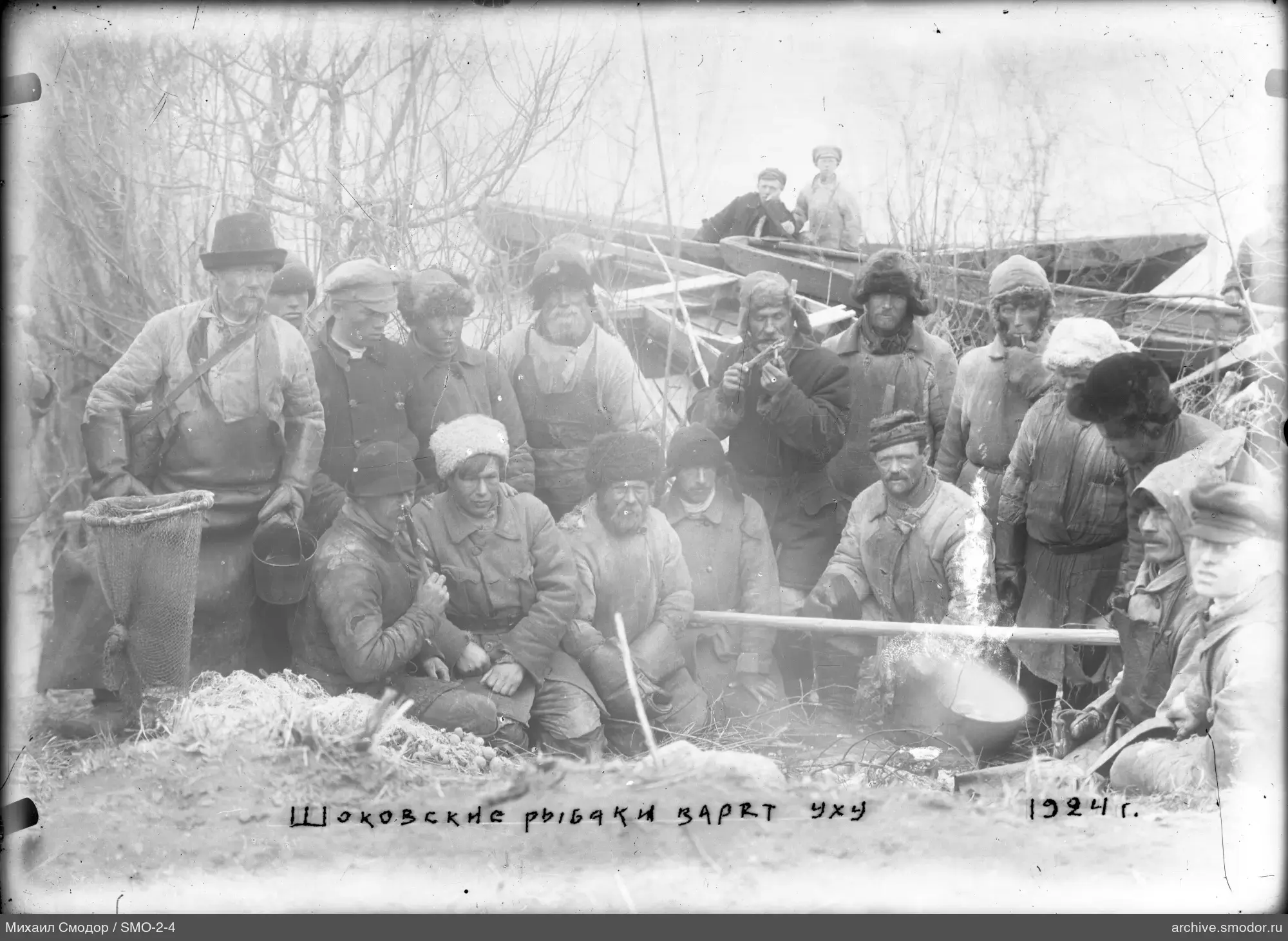 Group of men among bushes and boats