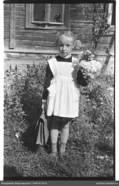 Mädchen mit Blumenstrauß vor Holzhaus