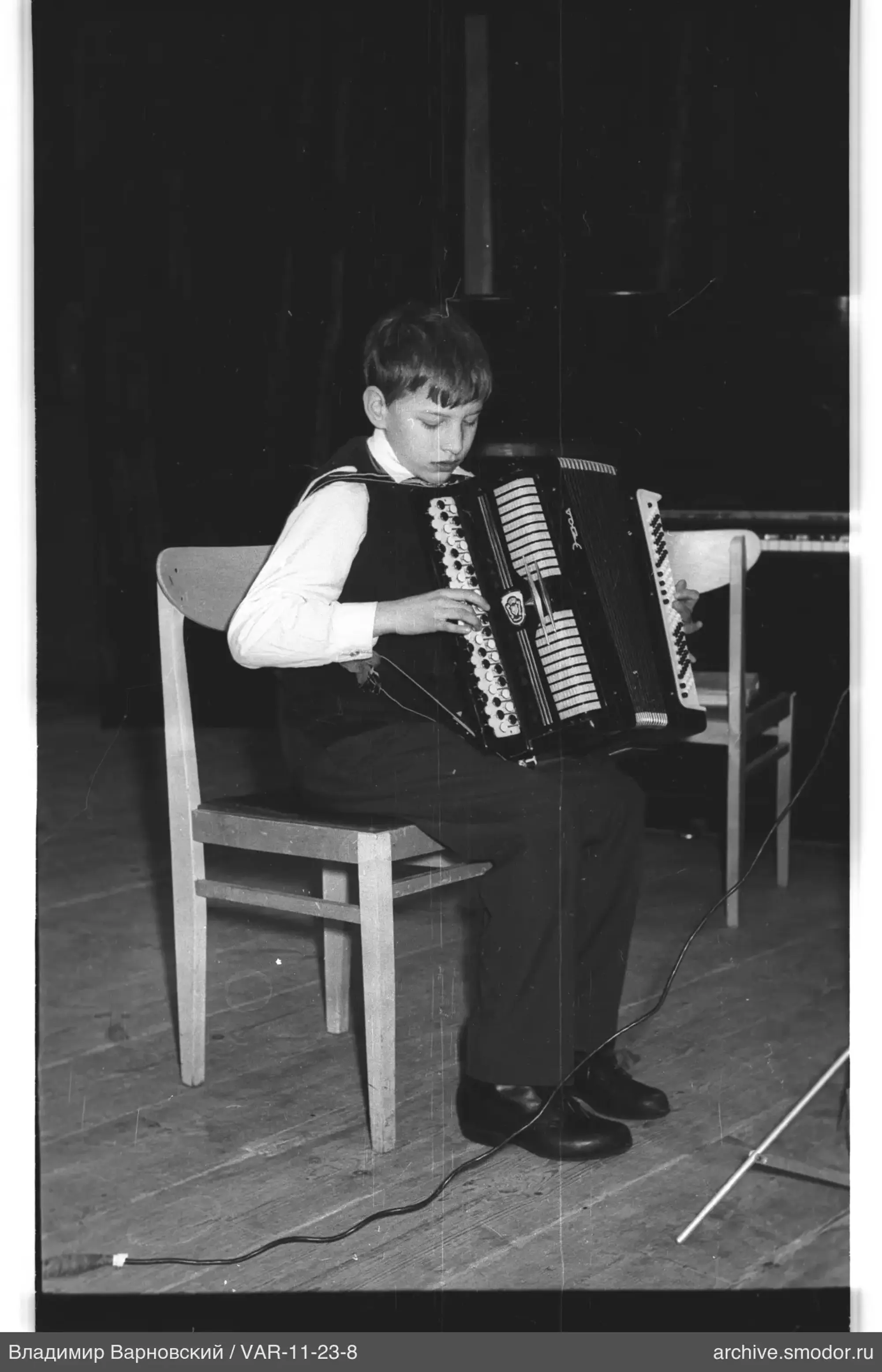Boy playing accordion on a chair