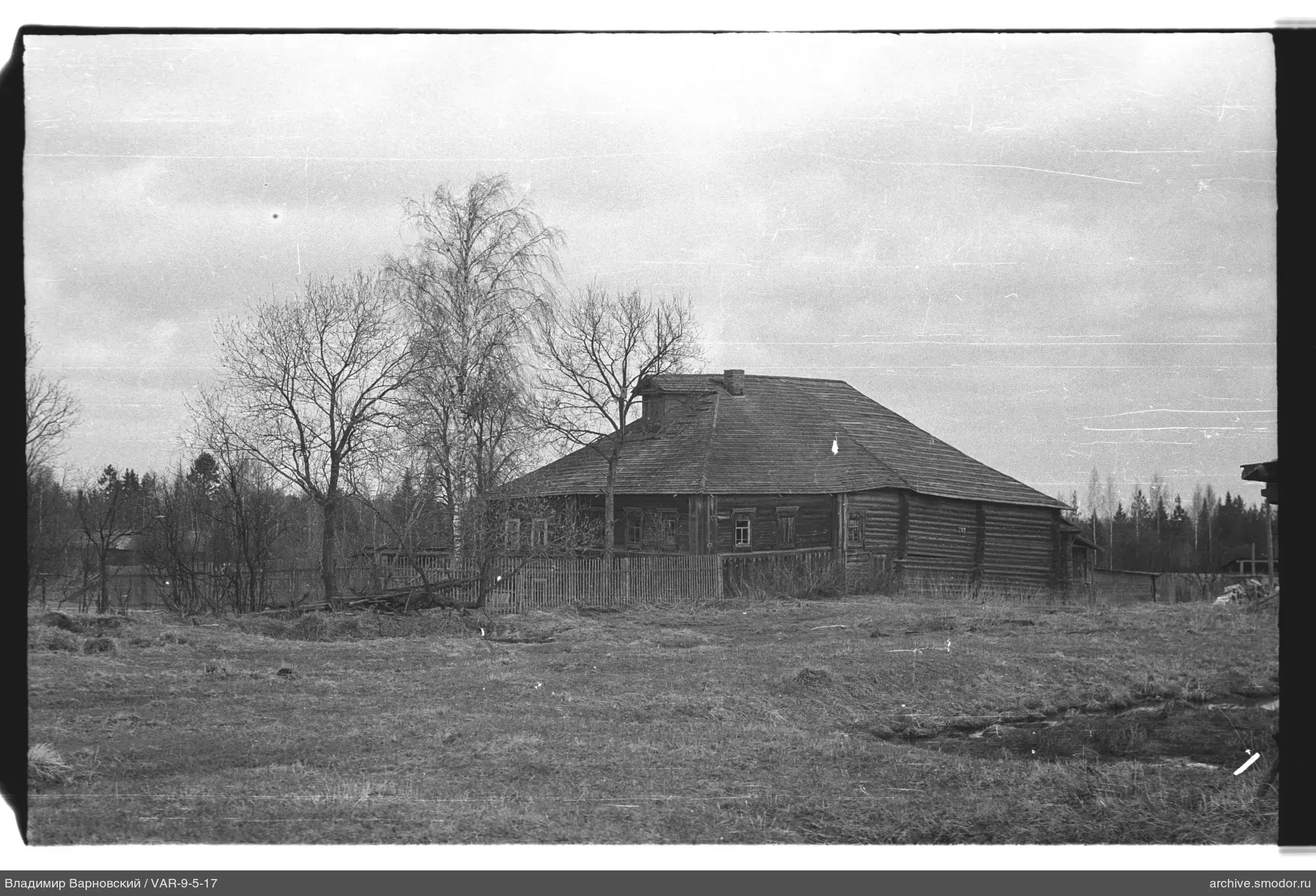 Holzhaus mit Zaun und Bäumen
