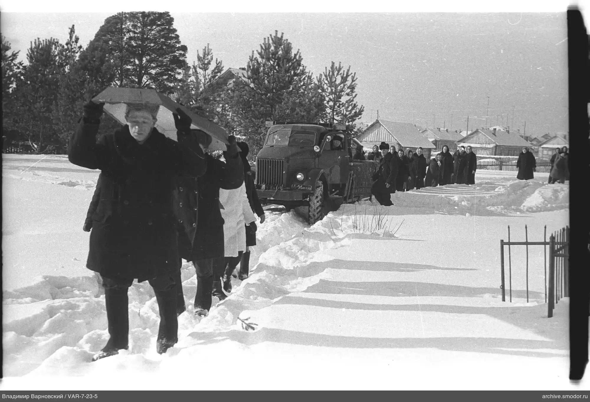 Group of people on snow-covered road by truck