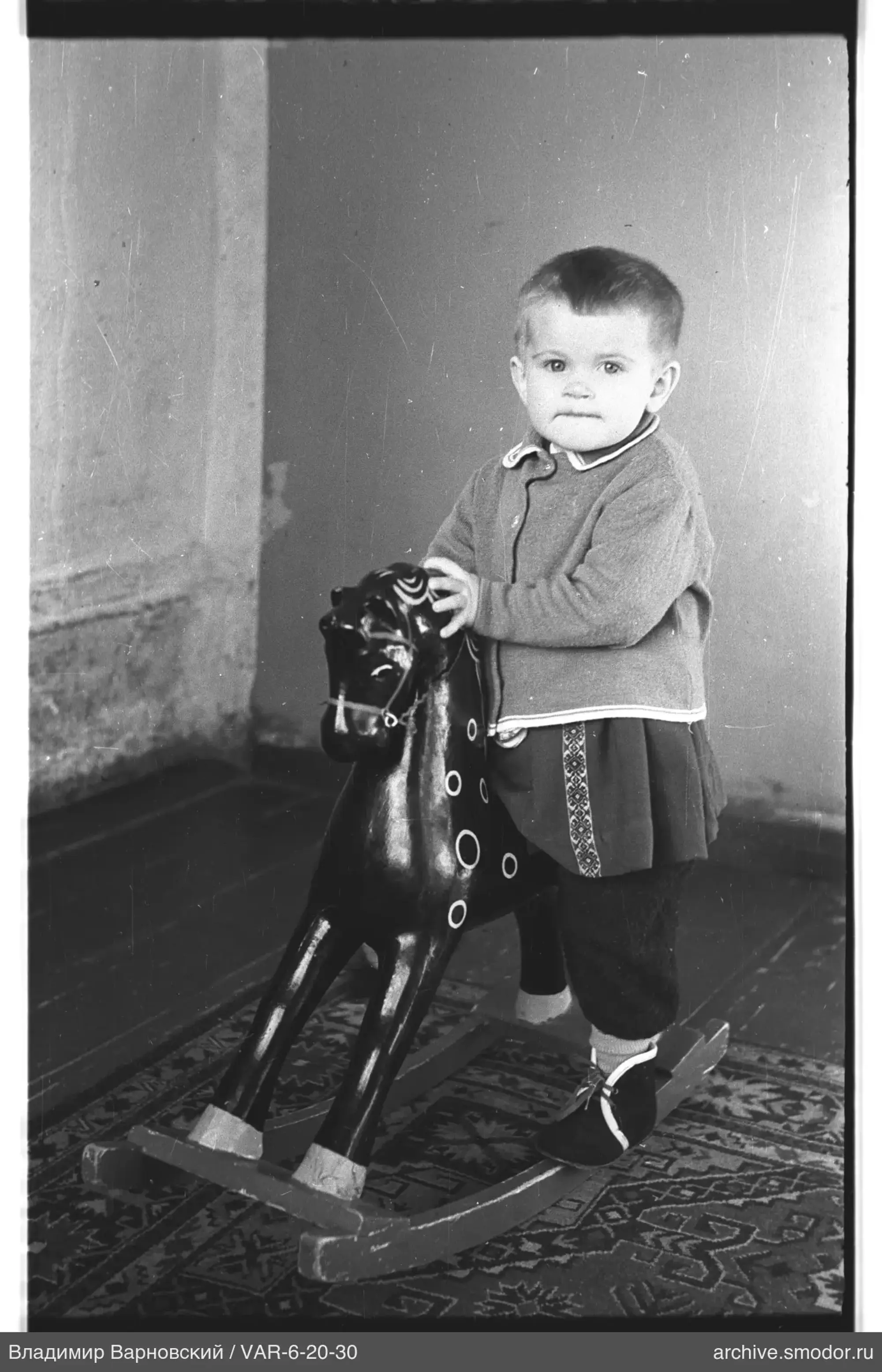 Child with rocking horse by wall