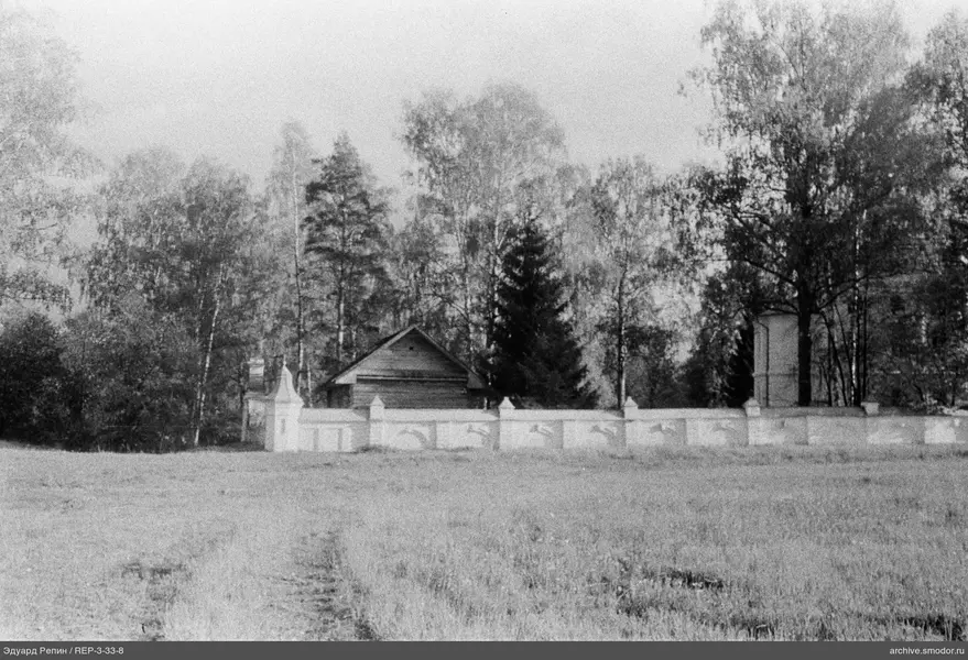 Holzhaus mit Steinzau und Bäumen