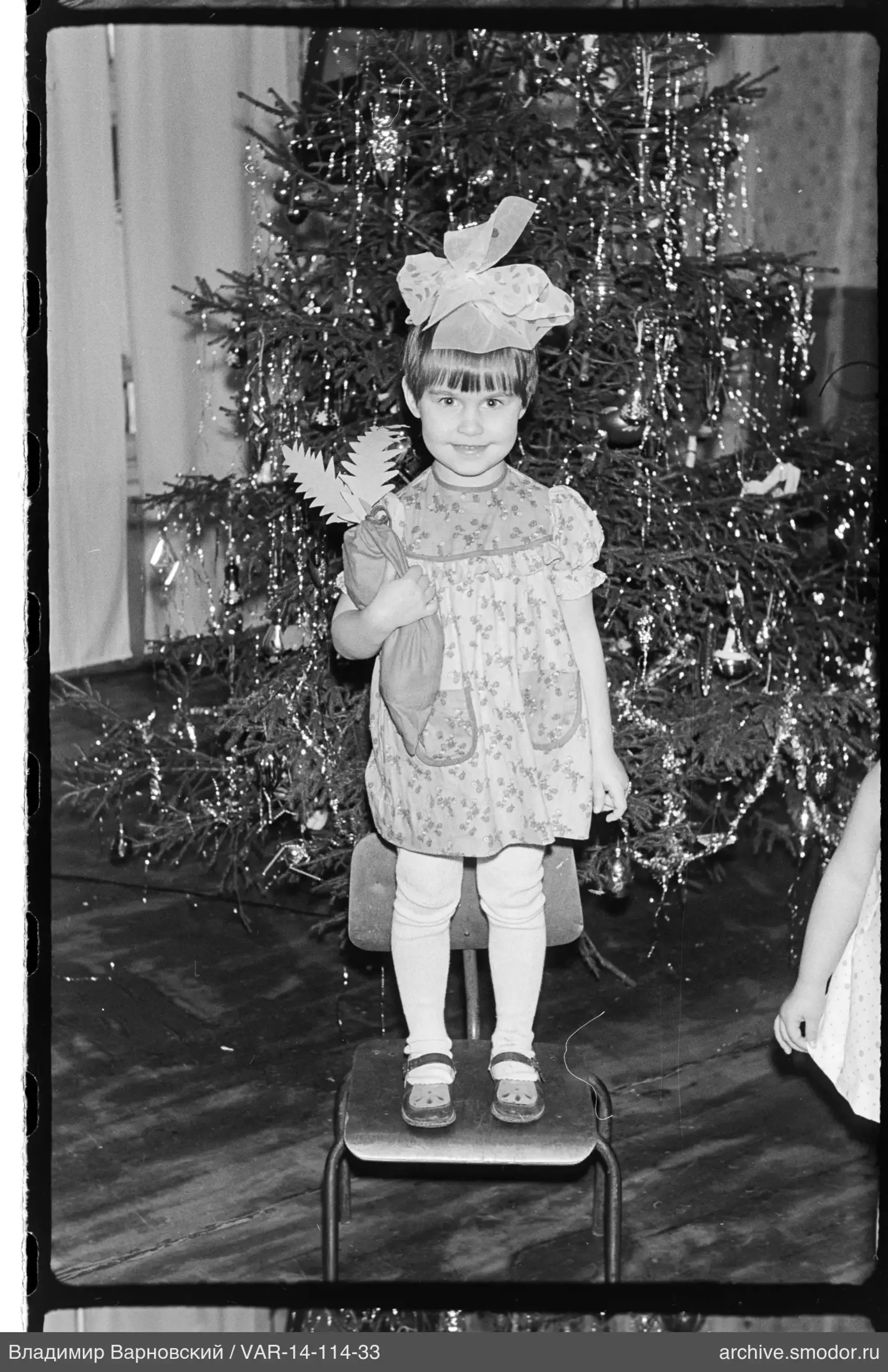 Mädchen mit Beutel vor geschmücktem Weihnachtsbaum