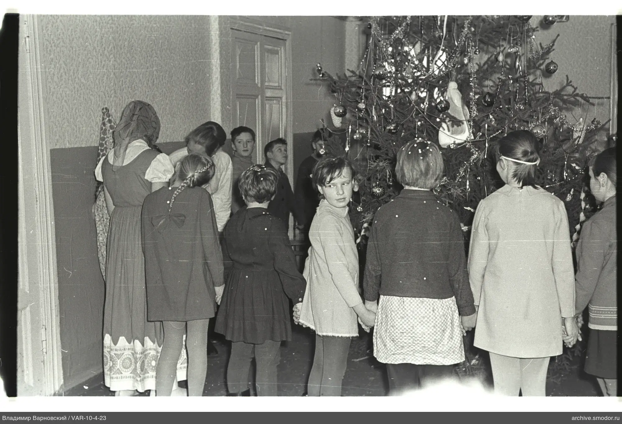 Kinder und Jugendliche um geschmückten Weihnachtsbaum