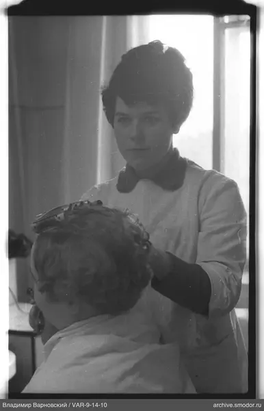 Frau mit Gerät am Kopf einer sitzenden Person
