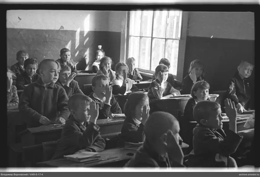 Kinder mit erhobenen Händen im Klassenzimmer