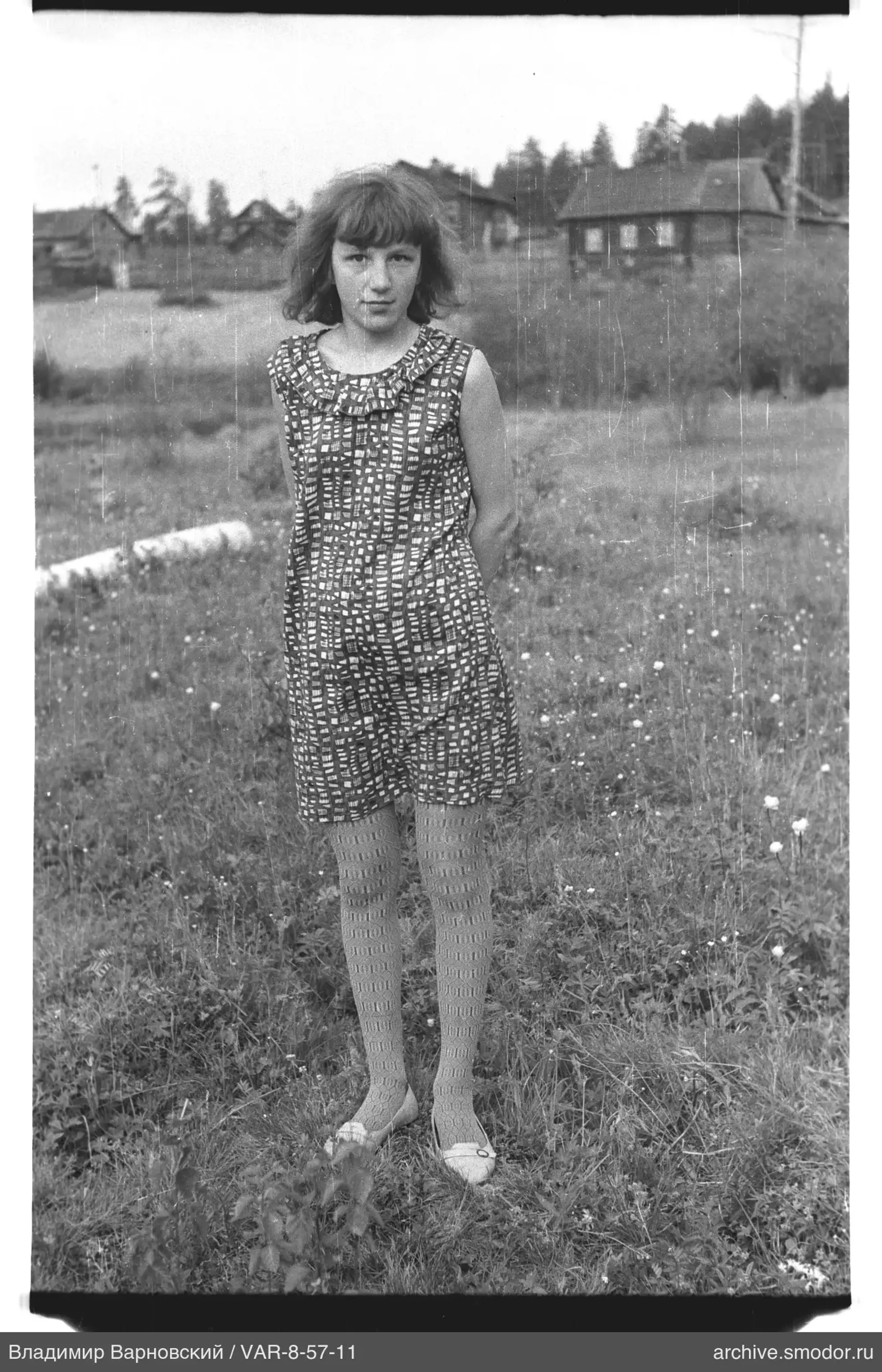 Girl standing on grassy field with houses and trees