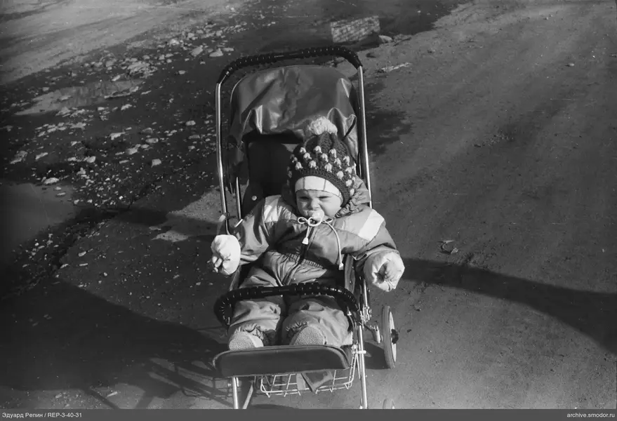 Kind im Kinderwagen auf unbefestigter Straße