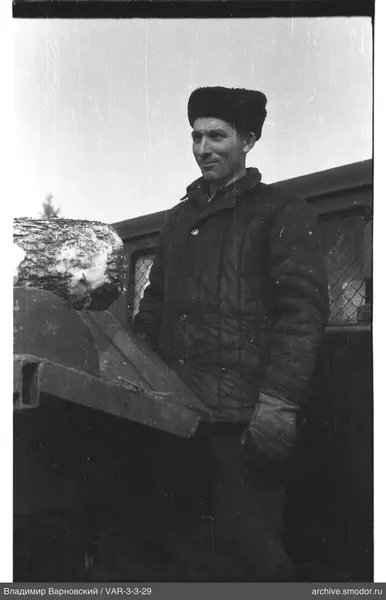 Man holding a piece of wood near metal structure