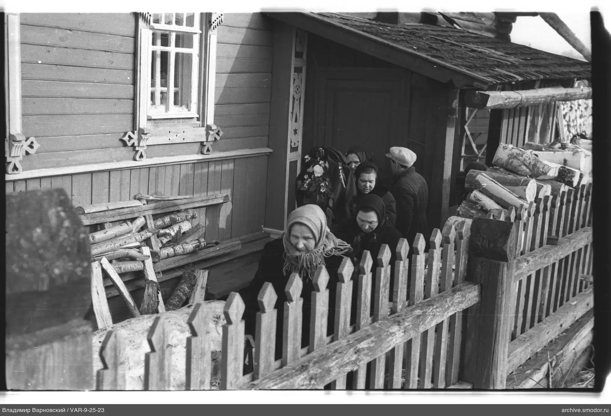 Gruppe von Menschen bei einem Holzhaus
