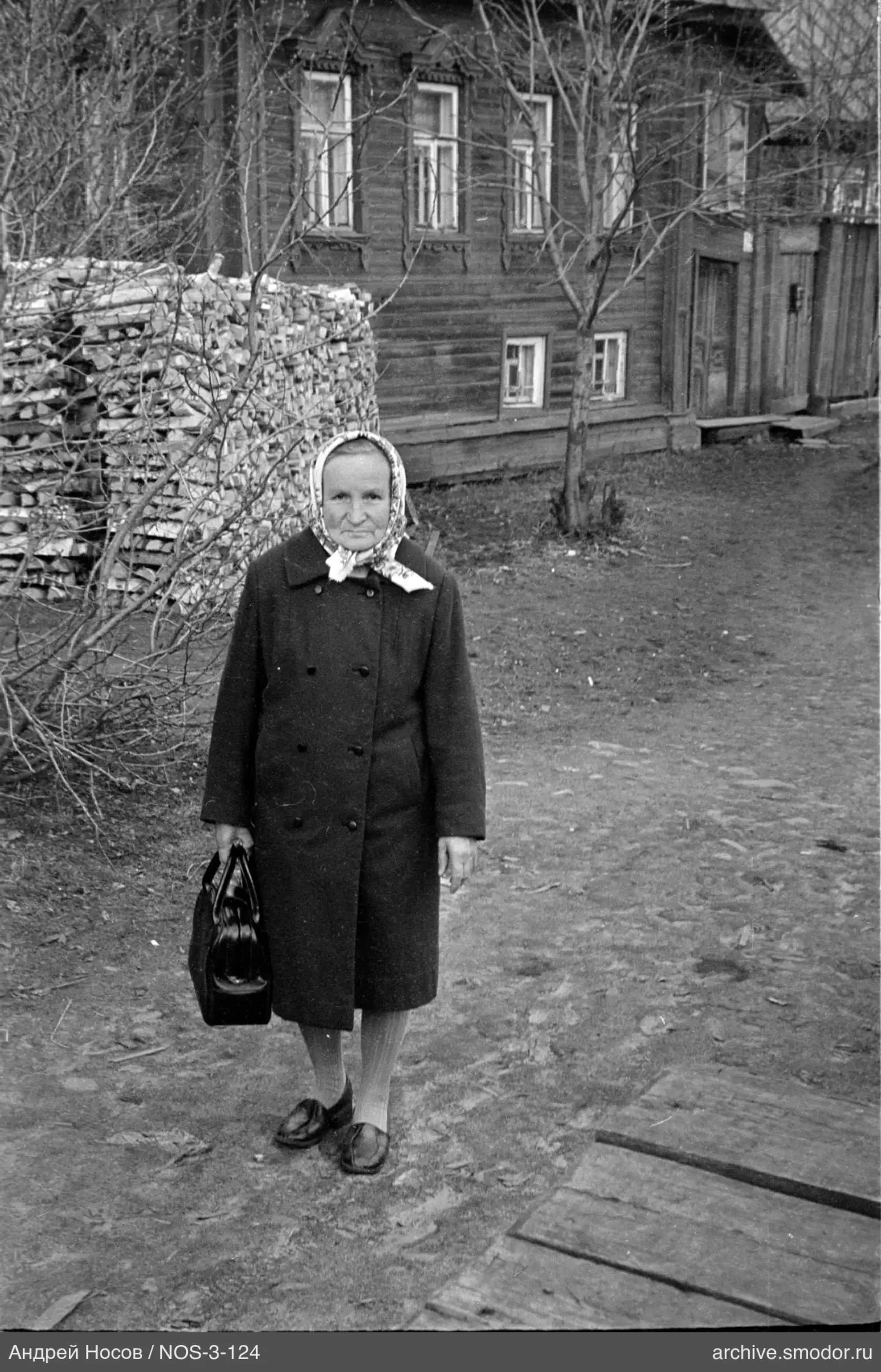 Женщина с сумкой у деревянного дома