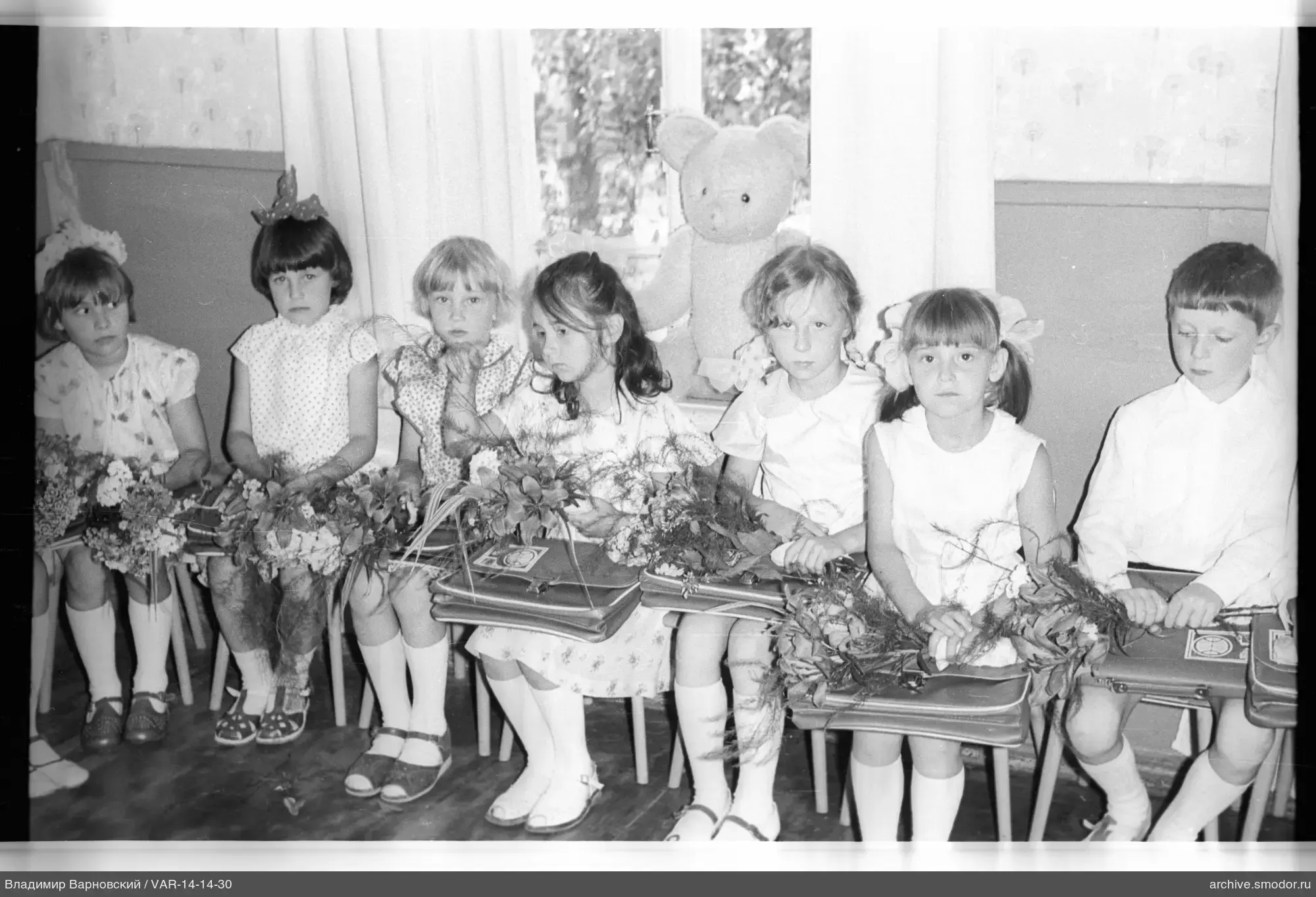 Gruppe von Kindern mit Blumen und weichem Bären
