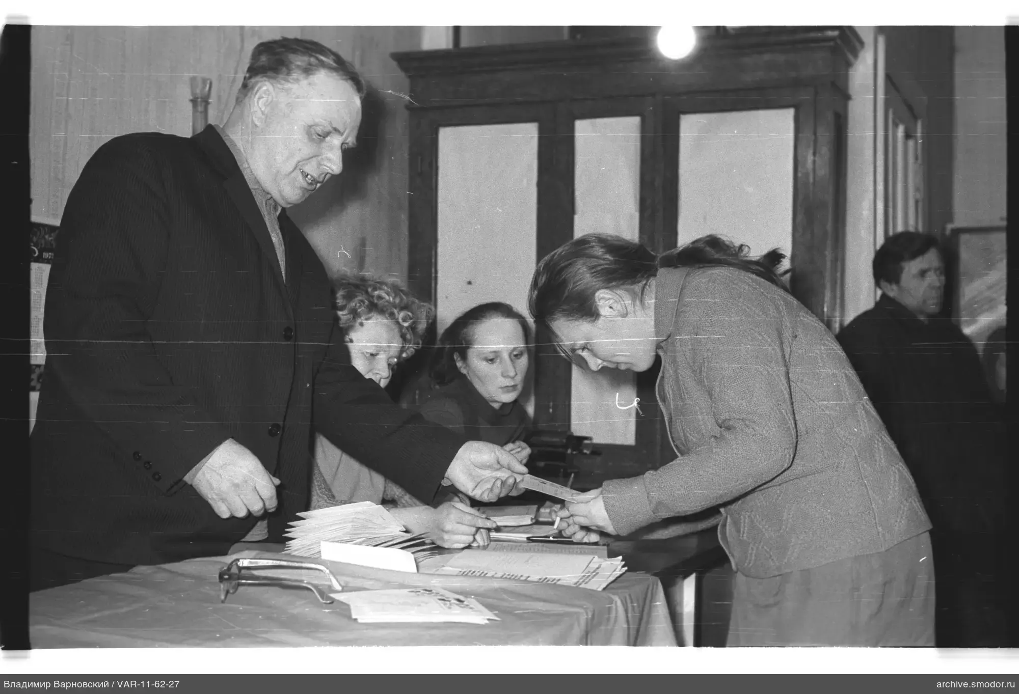 Man hands document to woman at table