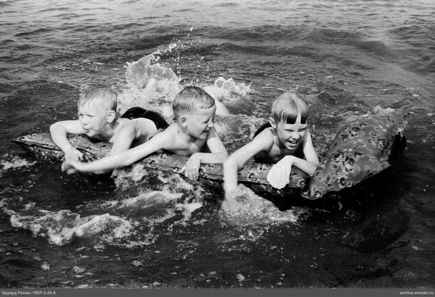 Drei Jungen auf einer aufblasbaren Matratze im Wasser