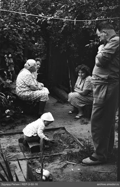 Kinder und Erwachsene beim Picknick am Zaun