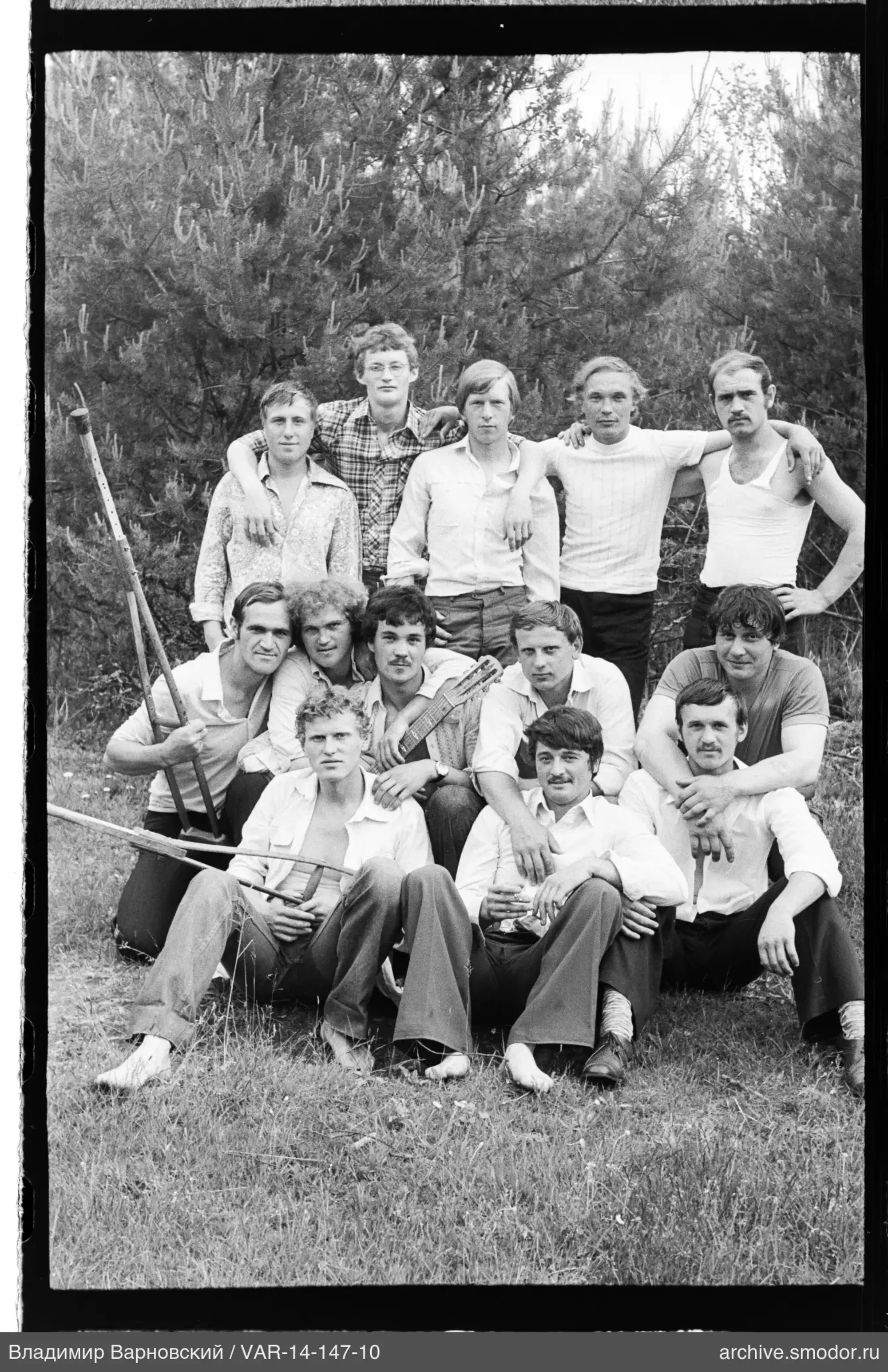 Gruppe von Männern auf Gras vor Nadelbäumen