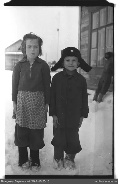 Kinder im Schnee bei einem Holzhaus