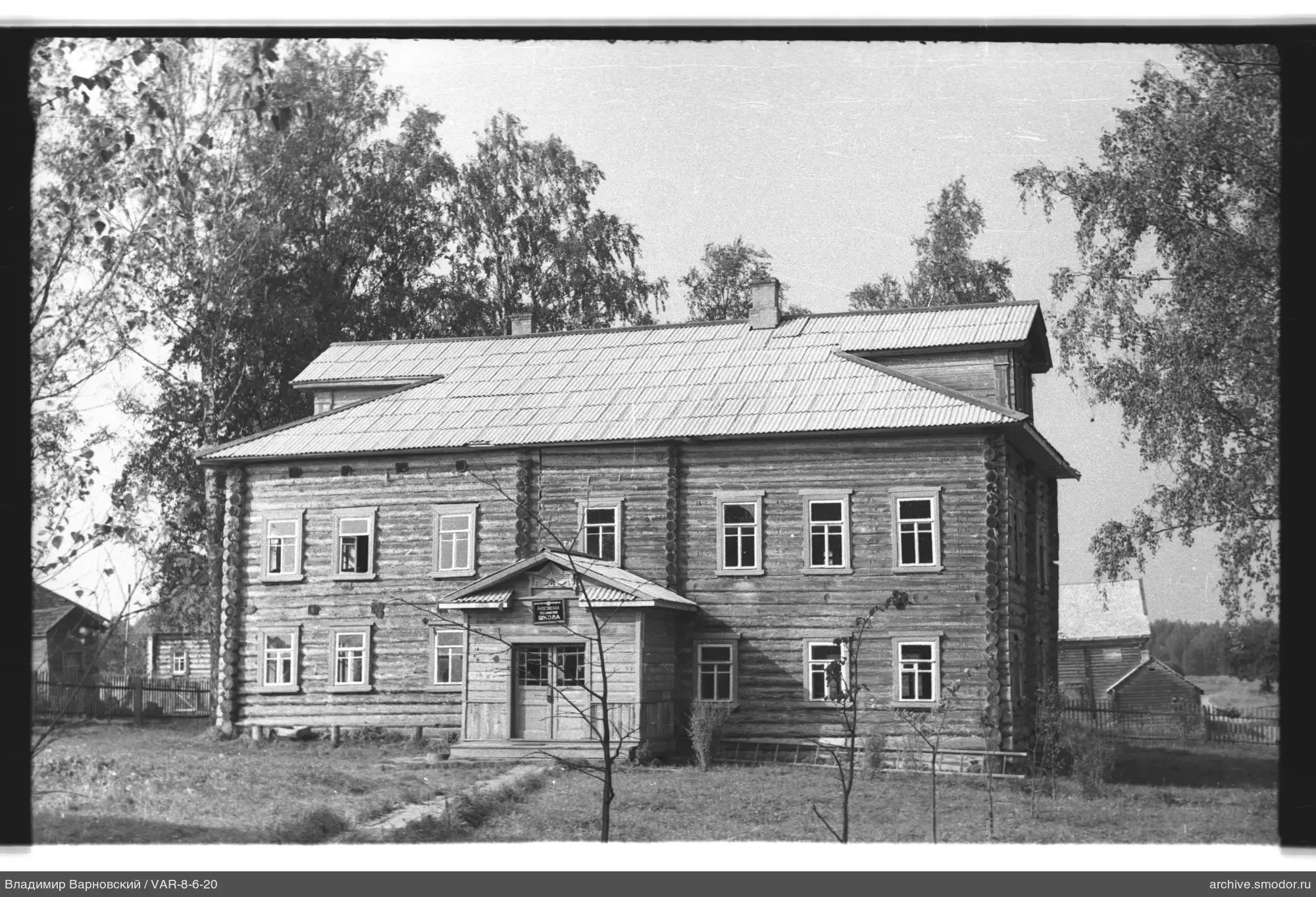 Zweistöckiges Holzgebäude mit Schild SHKOLA