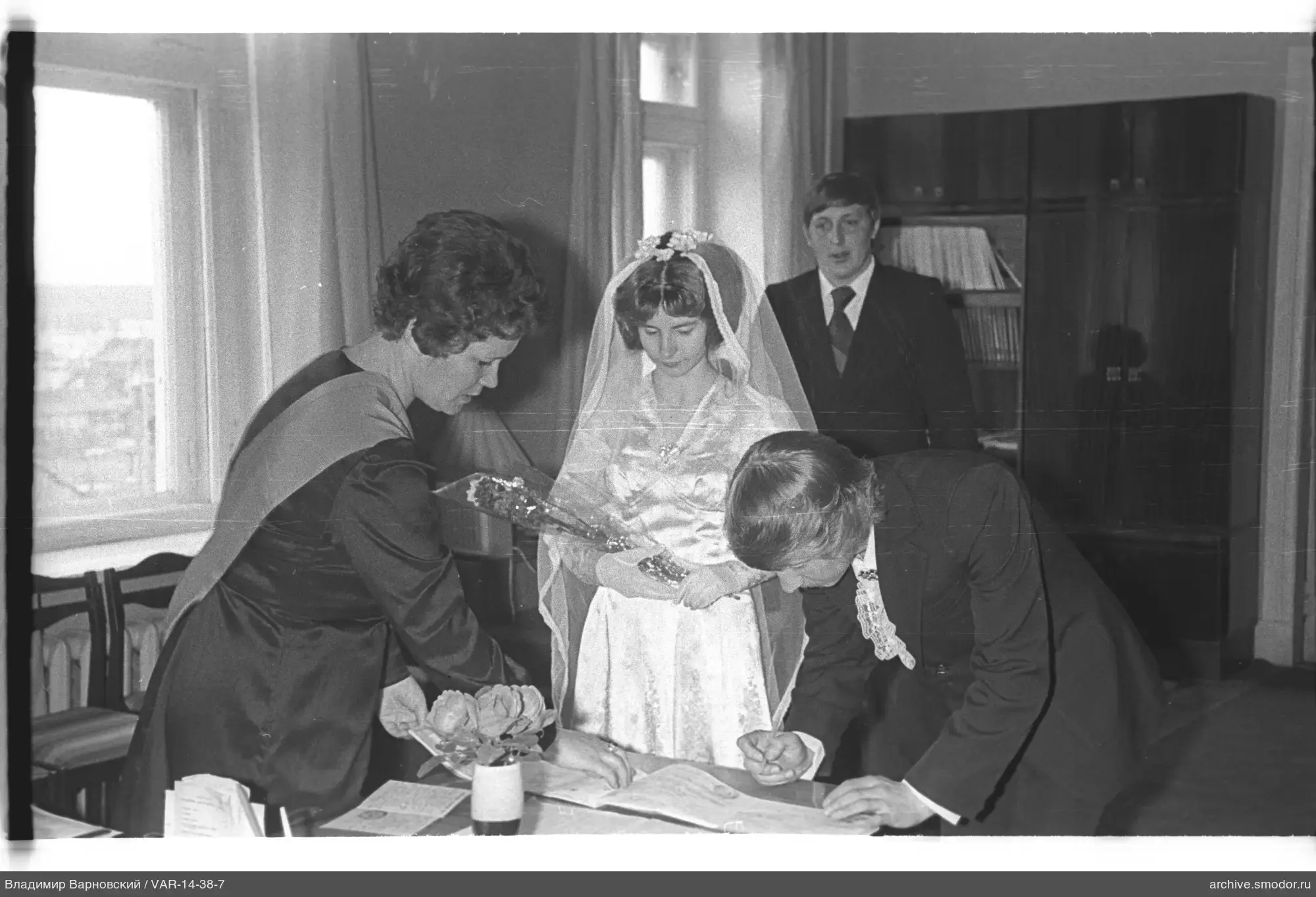 Woman handing bouquet and man signing document