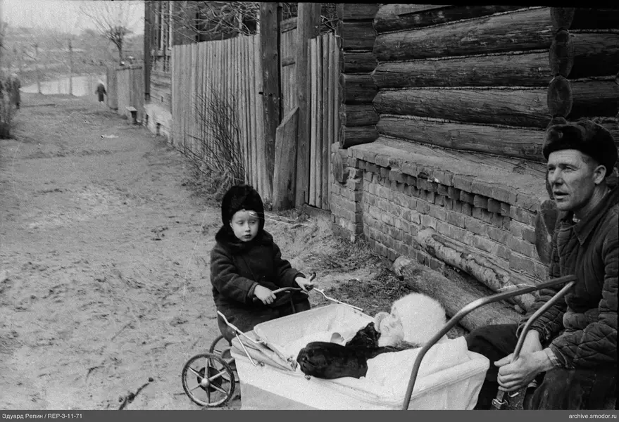 Mann und Kinder mit Kinderwagen am Haus
