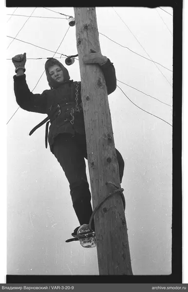 Woman on wooden pole with wires and insulators
